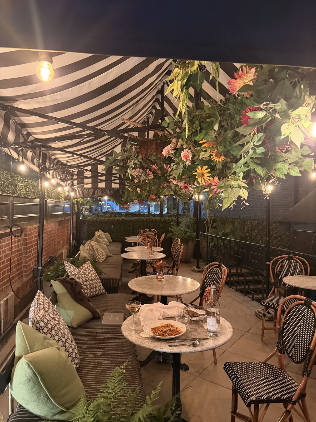 The Bloomsbury Hotel, London: Dalloway Terrace, covered outdoor restaurant, striped awning, floral canopy, marble bistro tables, 26 Sep 2026, 20:35