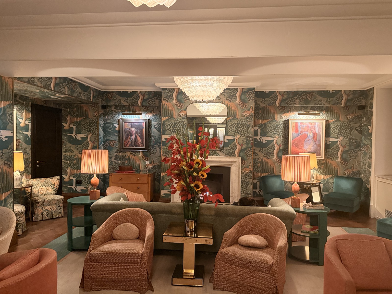 The Bloomsbury Hotel, London: fireplace lounge off the Coral Room, botanical wallpaper, marble Lutyens fireplace, two chandeliers, teal and terracotta chairs, 26 Sep 2026, 22:50